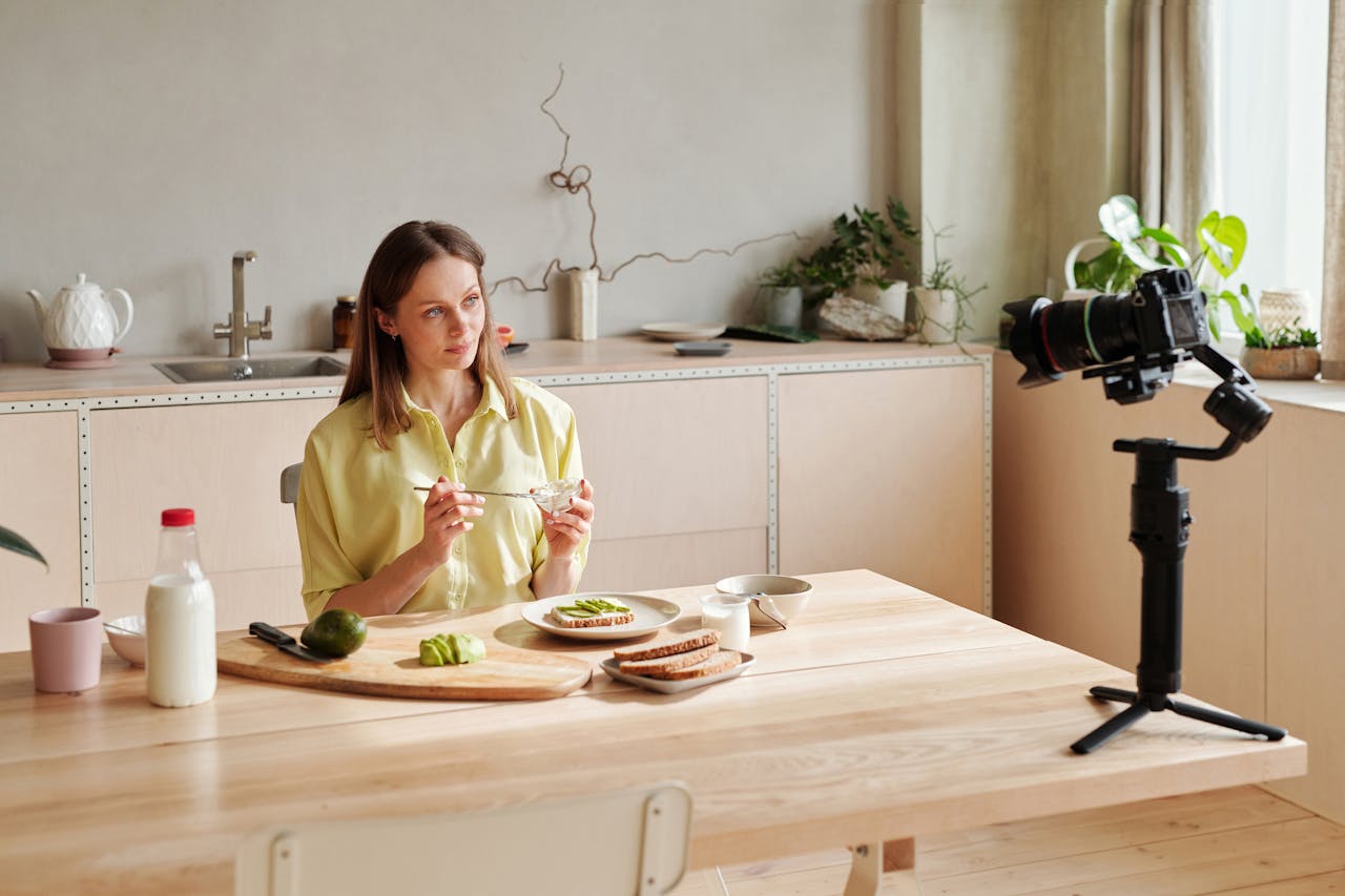 service-03 Woman recording a healthy breakfast vlog in a modern kitchen setting, featuring avocados.